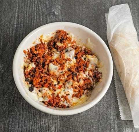 Bowl of homemade chorizo con queso with melted cheese blend and flour tortillas